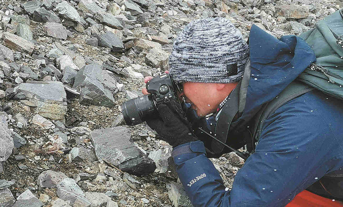 A scientist photographs plants on the slopes of Qomolangma, also known as Mount Everest. PHOTO PROVIDED TO CHINA DAILY